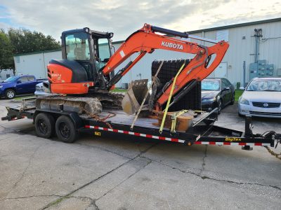 Digging vehicle on the back of a flatbed.